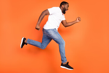 Fototapeta na wymiar Full length bdoy size profile side view of attractive cheerful guy jumping running fast speed isolated over bright orange color background