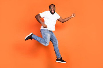 Fototapeta na wymiar Full body photo of brunette dark skin excited happy young man jump up tun isolated on orange color background