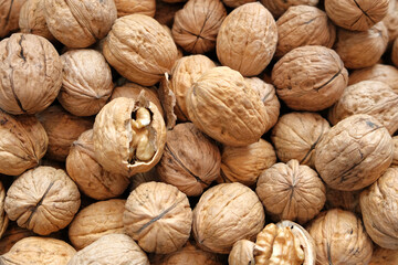 Walnut kernels and whole walnuts on rustic old wooden table