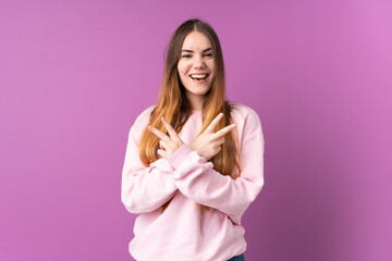 Fototapeta premium Young caucasian woman isolated on purple background smiling and showing victory sign