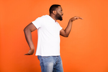 Profile side photo of happy funky dark skin man dance egyptian good mood isolated on orange color background