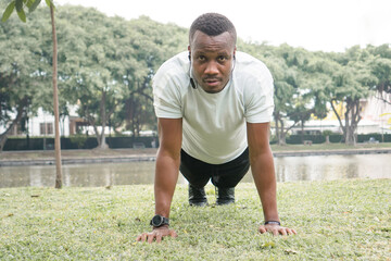 Naklejka premium African American sportsman pushups on green grass