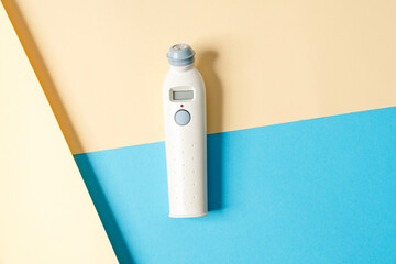 A close-up view of a thermometer for measuring body temperature lying on a colorful background