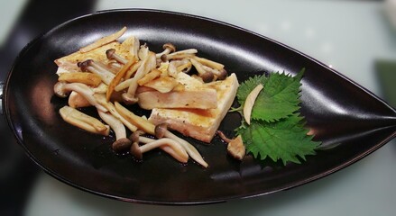 Dish of fried mushrooms and tofu served in a leaf-shaped platter