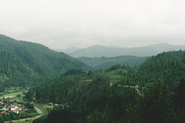 Colorful view from top hill to outskirts city near which winding railway is laid between hills and mountains