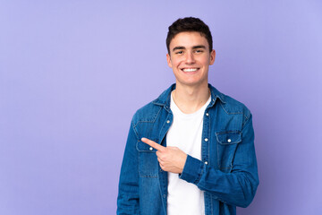 Teenager caucasian  handsome man isolated on purple background pointing to the side to present a...