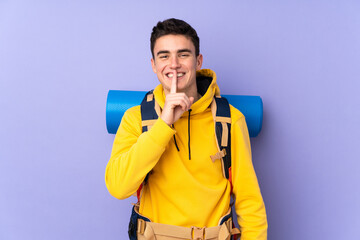 Teenager caucasian mountaineer man with a big backpack isolated on purple background doing silence gesture