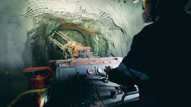 Industrial worker is using a boring mechanism to irrigate a mine