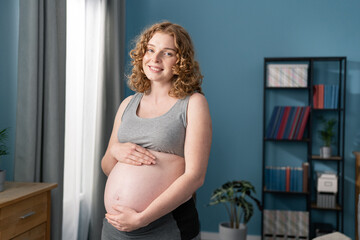 Pregnant Woman touching her belly. Happy Pregnant middle aged mother at home. Female holding her tummy. Healthy Pregnancy concept, Parenthood