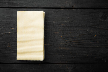 Dried uncooked lasagna pasta sheets, on black wooden table background, top view, flat lay, with copy space for text