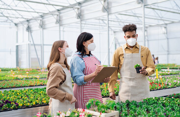 People working in greenhouse in garden center, coronavirus concept.