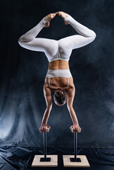 Flexible circus artist - female acrobat doing handstand on the back and smoker background. concept of willpower and passion.
