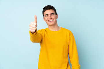 Teenager caucasian handsome man isolated on purple background with thumbs up because something good...
