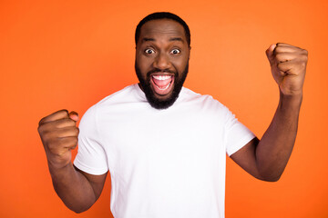 Portrait of attractive cheerful guy having fun rejoicing great success isolated over bright orange color background