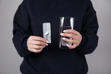 Woman with a glass of water in her hand and pill.