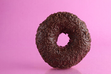 Chocolate berliner doughnut on a pink background with a place to text a copyspace breakfast dessert national dish