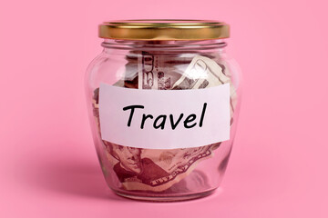 Money box with word TRAVEL on sticky note paper. Dollars in glass jar with savings label, financial, saving. Jar full of american dollar bills, cash, save money concept, expense planning, control.