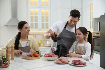 Happy family making dinner together in kitchen, father and daughter using modern meat grinder while...