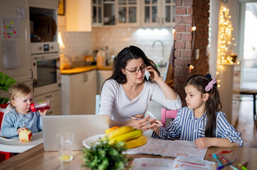 Mother with small daughter in kitchen, home schooling, office and distance learning concept.