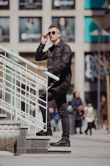 Young fashion man posing in a city street