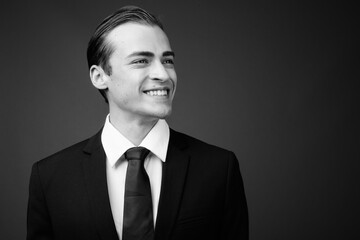 Young businessman against gray background in black and white