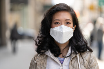 Asian woman wearing a mask serious face portrait on a city street