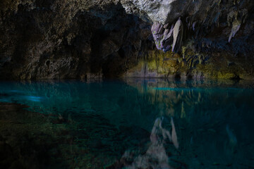 Light descends into the darkness of a submerged cavern with blue lake. Concept of travel and adventure.