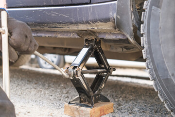 Lifting the car with a rhombic jack for service, car repair, wheel replacement.