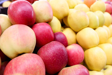 Many yellow and red apples lying on counter of store closeup