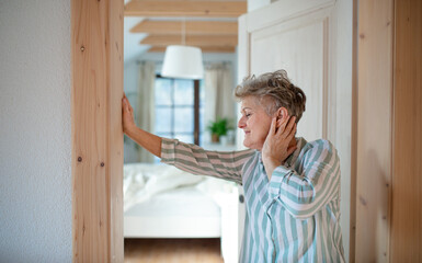 Senior woman standing by door at home, getting up in the morning.