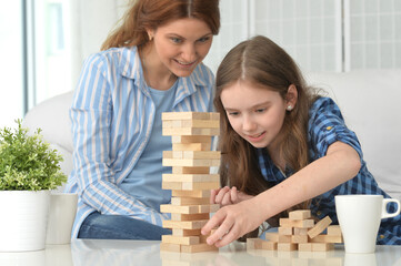 Happy girl and mother playing with blocks at home
