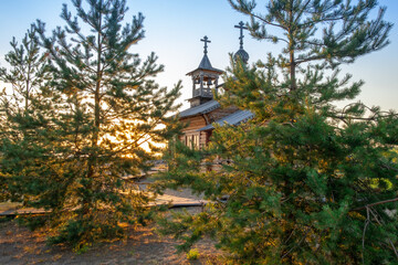 Fototapeta na wymiar Small wooden russian orthodox church. Wooden orthodox church against blue sky on sunny day