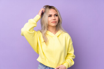 Teenager girl wearing a yellow sweatshirt over isolated purple background having doubts and with confuse face expression