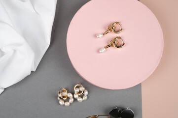Jewelry with pearls on pink gray background. Fashion flat lay