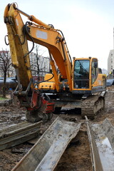 Fototapeta na wymiar Yellow crawler excavator on a construction site, Bolshevikov Avenue, Saint Petersburg, Russia, April 2021