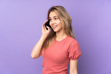 Fototapeta premium Teenager Russian girl isolated on purple background keeping a conversation with the mobile phone with someone