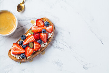 Toast with cream cheese, strawberries, blueberries and maple syrup, top view. Breakfast food concept.