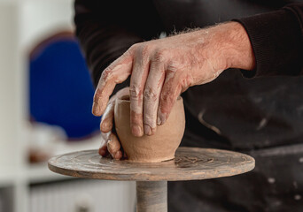 Man working on pottery wheel with clay