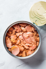Close up of tin can of tuna fish, top view, white marble background. Canned food concept.