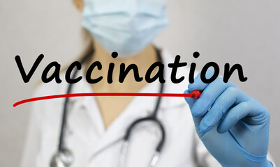 The doctor in blue glove writes to the text VACCINATION.