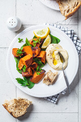 Baked sweet potato slices with spinach and hummus on white plate.