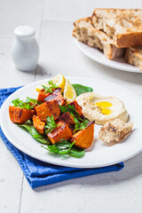 Baked sweet potato slices with spinach and hummus on white plate.