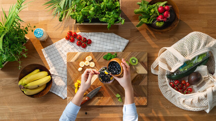 Top view of unrecognizable woman preparing fruit smoothie, sustainable lifestyle.
