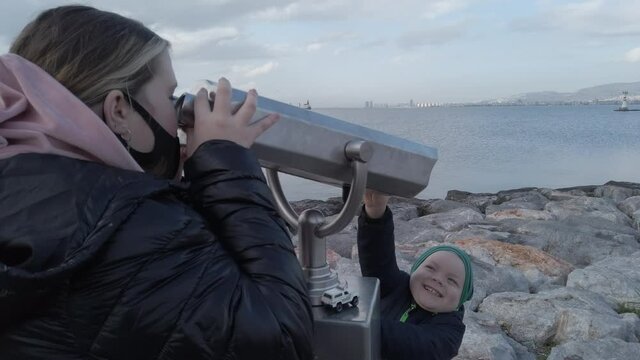 Izmir, Turkey - January 2021: A girl looks through binoculars on the waterfront. Tourist binoculars.