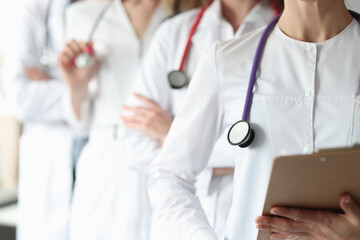 Group of doctors with stethoscope around their neck stands in clinic closeup