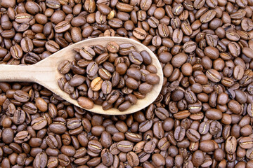 Fototapeta premium Coffee beans and wooden spoon background.Roasted coffee beans texture.Morning coffee
