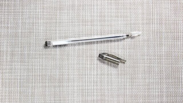Stop motion animation. Picking up and twisting a ballpoint pen. A rod is inserted into the ballpoint pen. Top view.