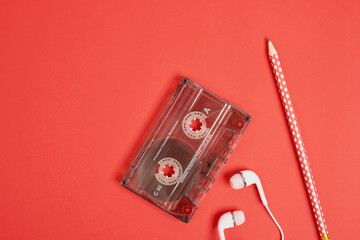 smartphone pencil headphones and audio cassette on red background, memories concept