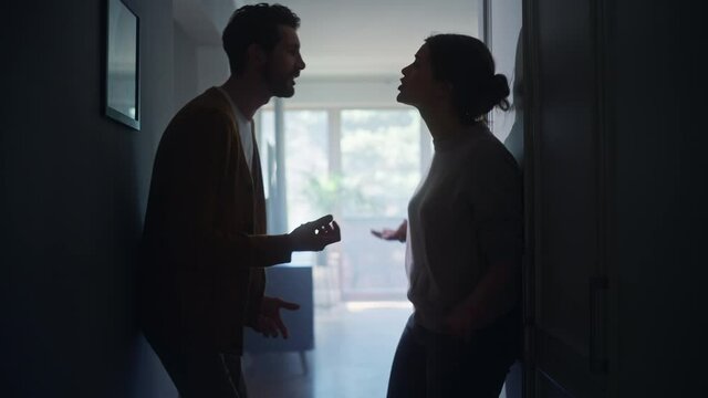 Young Couple Arguing and Fighting. Domestic Violence and Emotional abuse Scene, Stressed Woman and aggressive Man Screaming at Each other in the Dark Hallway of Apartment. Dramatic Scene