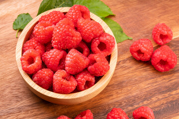 Raspberry fruit on wooden bowl in Wooden background, Raspberries with leaves on Wooden background.